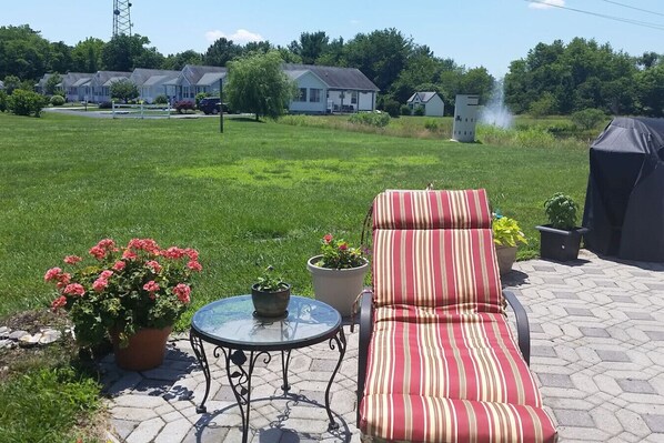 A patio with a striped lounge chair, a small table, and potted plants.
