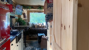 Cocina de madera estrecha con un refrigerador rojo, estufa y pileta. Se ve un ventanal con vista a la vegetación.