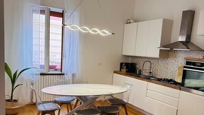 A modern kitchen with white cabinets, a round dining table with chairs, and a built-in oven. - Emilù Guest House In the center of Pescara 300 m. from the sea Entire apartment. (Pescara)