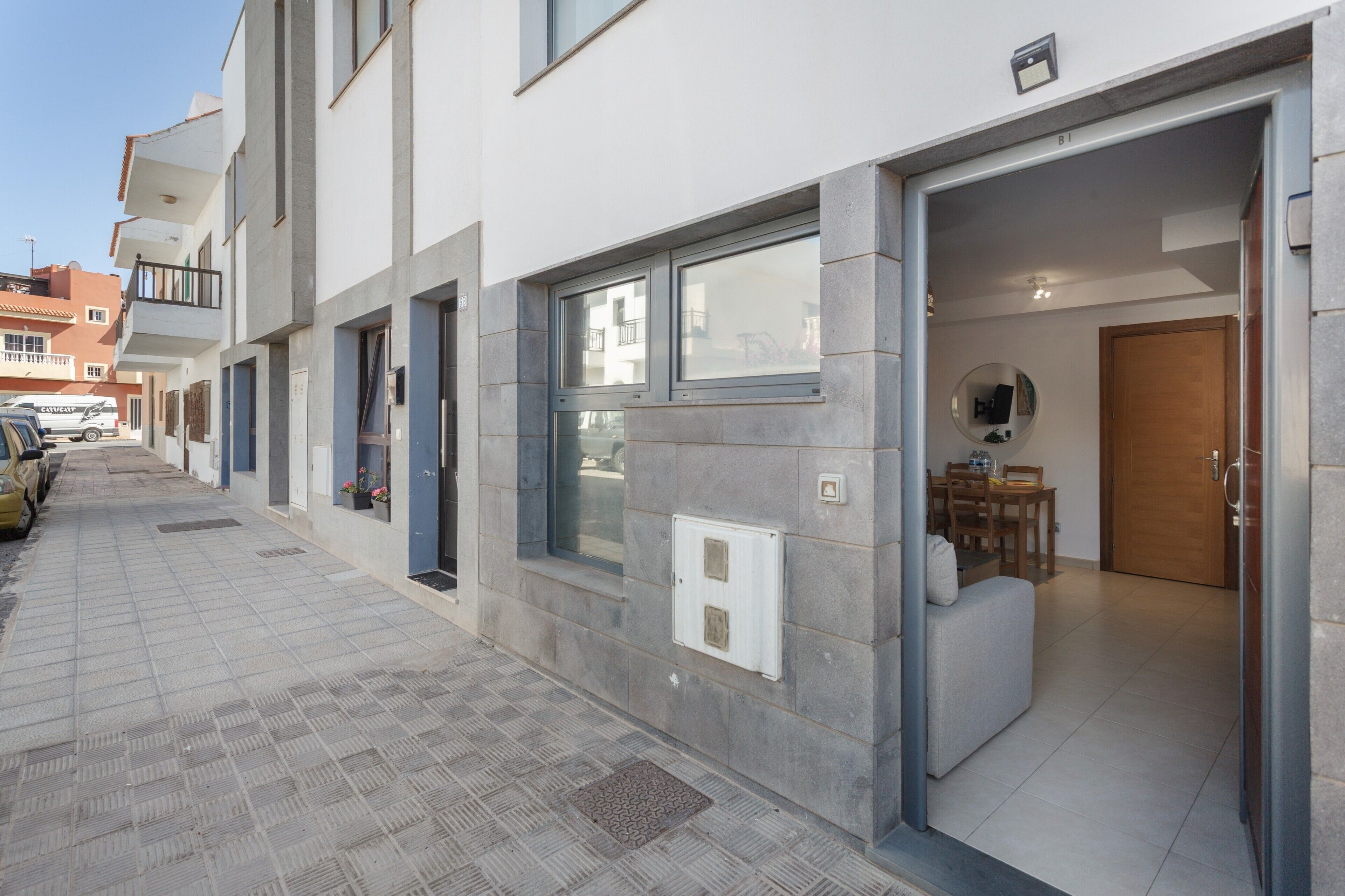 A modern building with a tiled exterior, a visible entrance, and a small outdoor seating area.