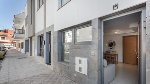 Un edificio moderno con rivestimento in tegole, un ingresso ben visibile e una piccola area esterna con posti a sedere.