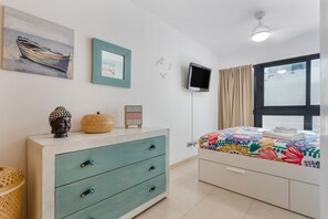 Une chambre à coucher avec un lit, une commode, un téléviseur et une fenêtre.