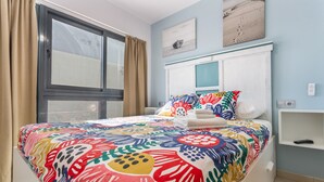 Una camera da letto con un letto grande, una finestra con tende, un comodino e una mensola a parete.