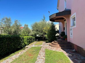 A house with a paved pathway leading to a set of stairs.