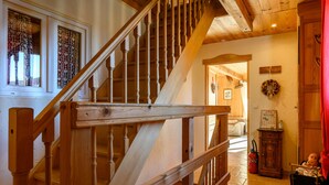 A wooden staircase with a handrail, a red curtain, and a calendar on a wall.