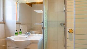 Een badkamer met een wastafel, spiegel en douche.