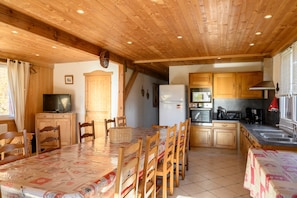 Un interior de madera con una mesa de comedor, sillas, televisor, zona de cocina y armarios de madera.
