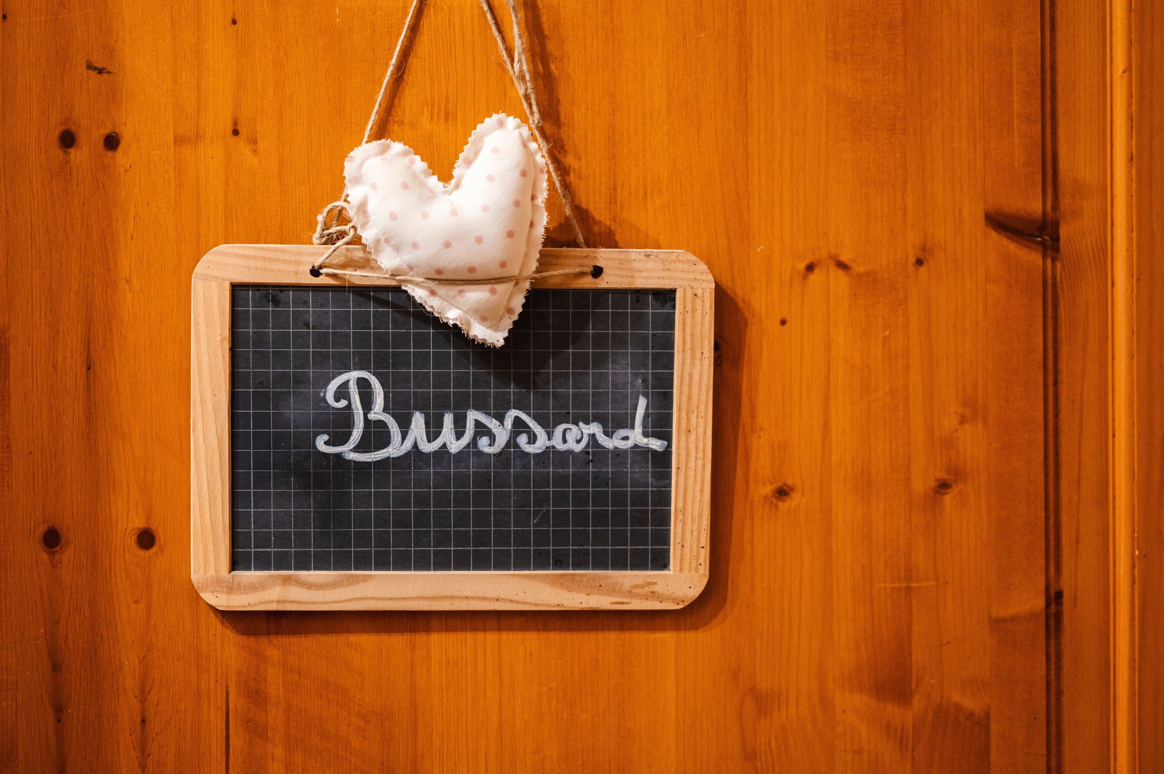 Eine Holzwand mit einer Kreidetafel, auf der das Wort 'Busard' steht.
