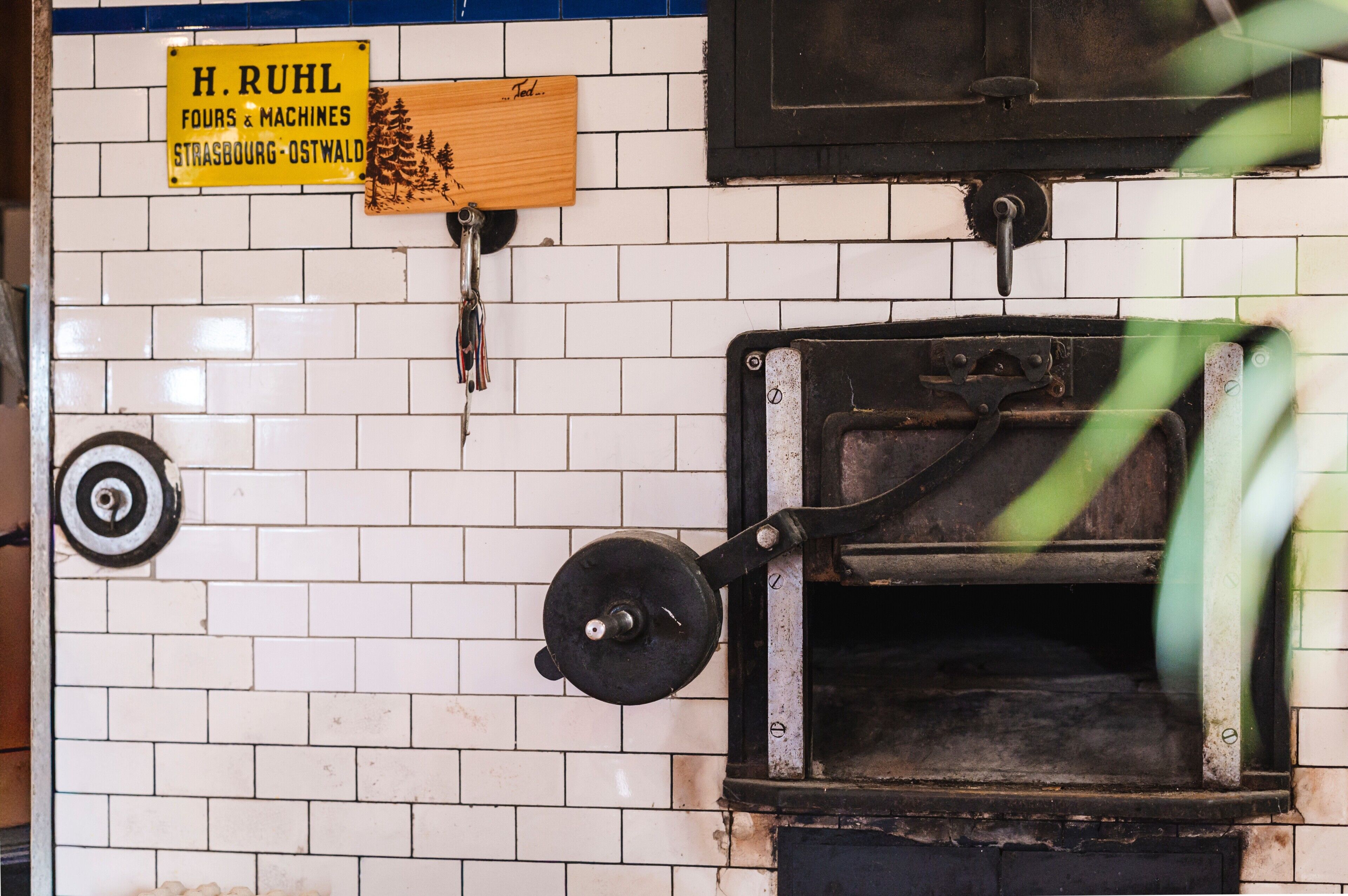 A vintage brick wall with a sign for H. Ruhl Fours & Machines, a metal door, and a circular object.