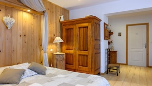Une chambre à coucher avec une armoire en bois, un lit avec des oreillers, une table de chevet et une lampe.