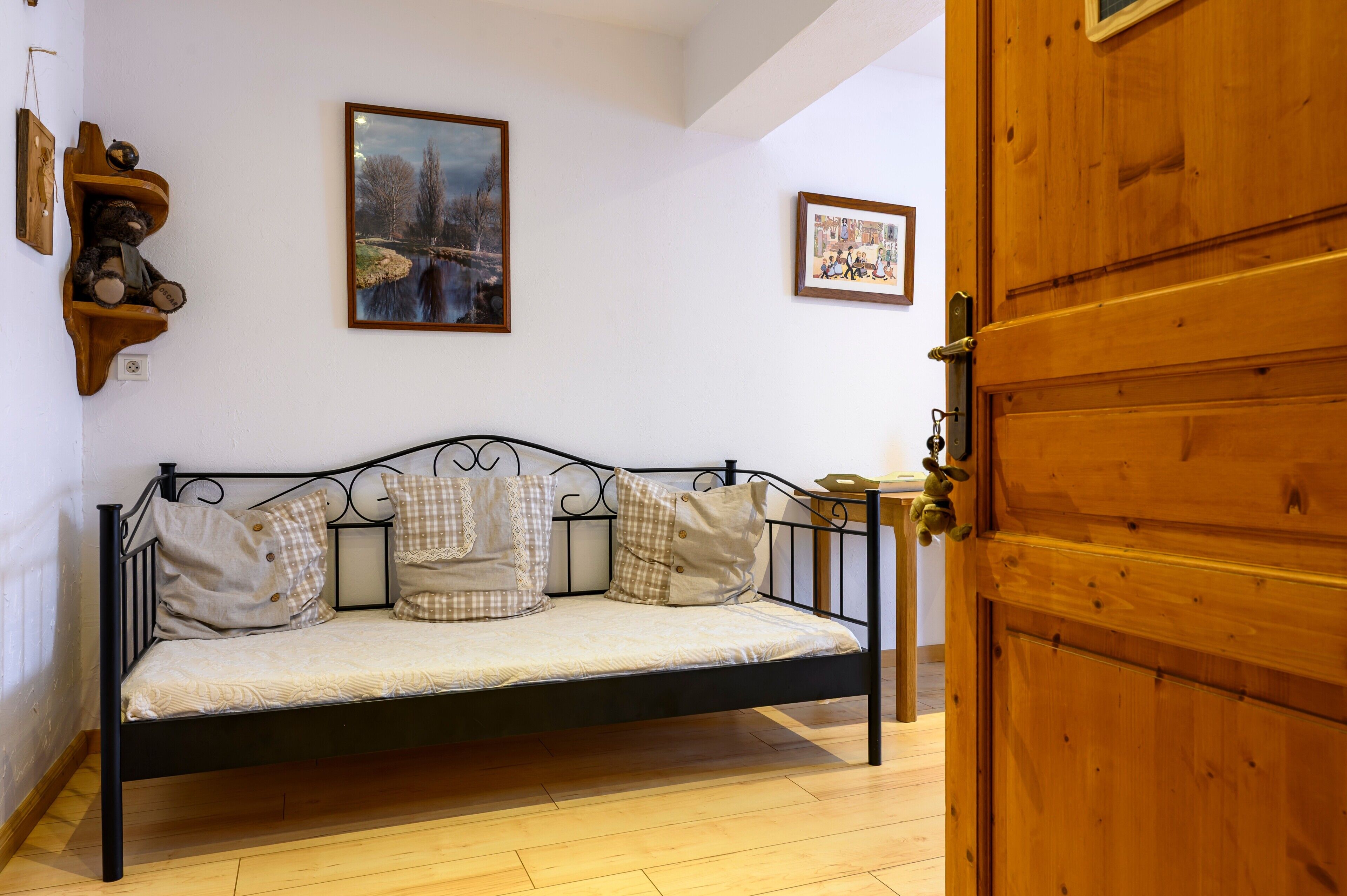 Een bed met hoofdeinde, een houten deur en twee ingelijste foto's aan de muur.