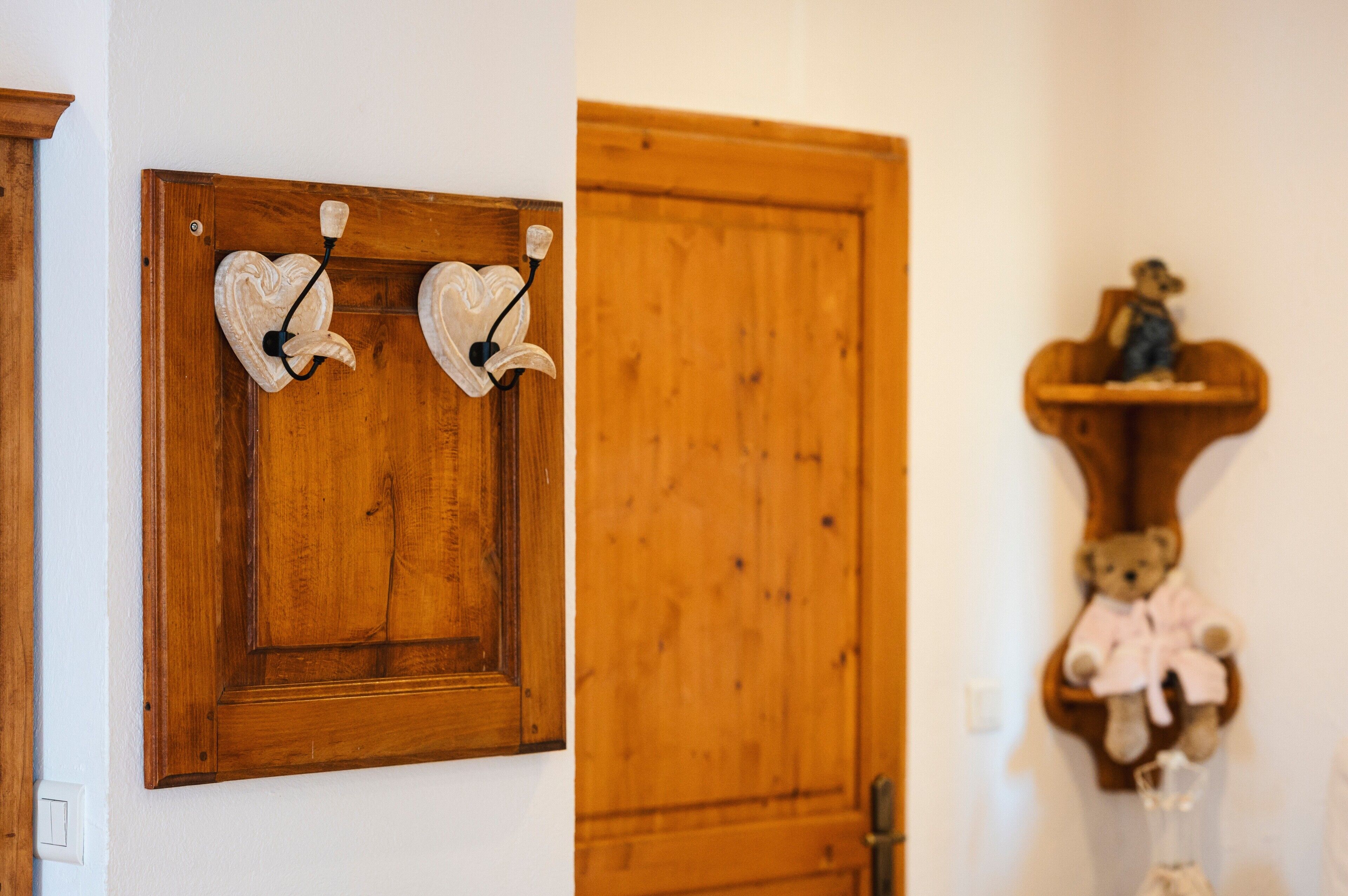 A wooden door with a heart-shaped decoration and a shelf with a teddy bear.