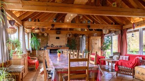 Un coin repas en bois avec une longue table, des chaises et un canapé rouge.