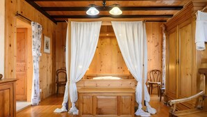 A wooden room with a bed, two chairs, a wooden cabinet, and a wooden ceiling. - Guest Room and Table d'hôtes “À L'ancienne Boulangerie - Millet” (Elsenheim)