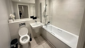 A modern bathroom with a toilet, sink, and bathtub. - Salford City Retreat - 2 Bedroom Apartment (Salford)