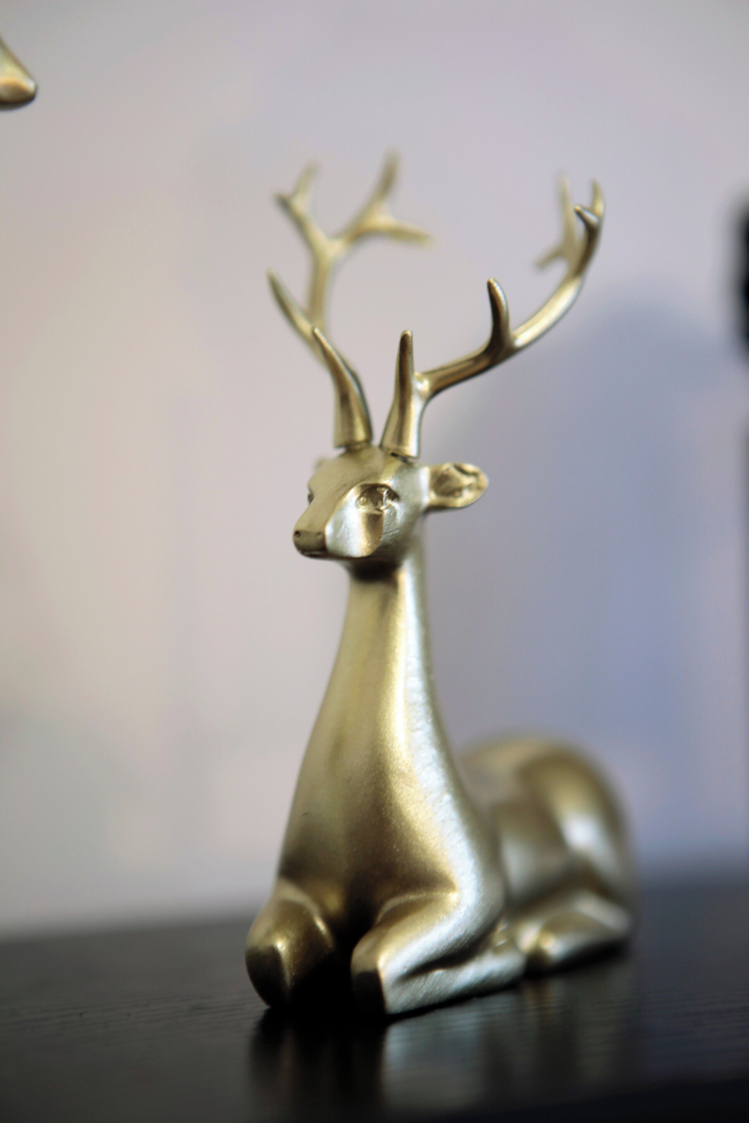 A metallic deer figurine with antlers on a dark surface.