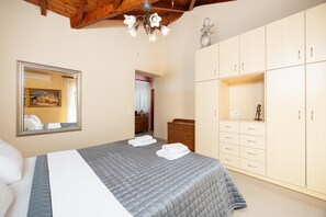 A bedroom with a bed, a wardrobe, a mirror, and a chandelier.
