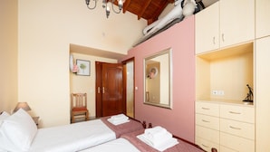 Ein Hotelzimmer mit zwei Betten, einem Holzschrank, einem Spiegel und einer Tür zu einem weiteren Raum.