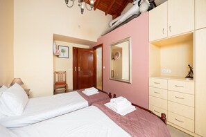 A hotel room with two beds, a wooden wardrobe, a mirror, and a door leading to another room. - Villa Aliona - Four Bedroom Villa, Sleeps 8 (Ionian Islands)