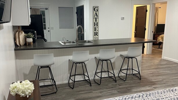 Une cuisine moderne avec un coin bar, des meubles blancs et un panneau décoratif.