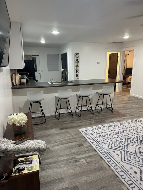 A modern kitchen with a bar area, white cabinetry, and a decorative sign.