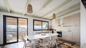 Een moderne keuken met witte kasten, een eettafel met stoelen en een uitzicht door grote ramen.