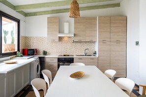 Una cucina moderna con isola centrale, mobili in legno, forno a microonde e lampadario.