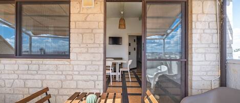 A balcony with a wooden table, a bench, and a plastic chair.
