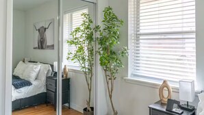 A bedroom with a bed, a desk, a chair, a mirror, and two potted plants. - Farm House - 1 min to Integris/State Fair/downtown (Oklahoma City)
