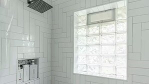 A bathroom with white herringbone-patterned tiles, a showerhead, and a window with frosted glass. - Farm House - 1 min to Integris/State Fair/downtown (Oklahoma City)