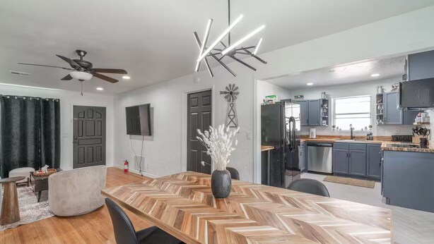 A modern kitchen with grey cabinets, a black refrigerator, and a wooden dining table with chairs. - Farm House - 1 min to Integris/State Fair/downtown (Oklahoma City)
