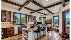 A spacious kitchen with wooden floors, a large island with bar stools, and a view of the outdoors. - Luxury House in Gated Community (Carbondale)