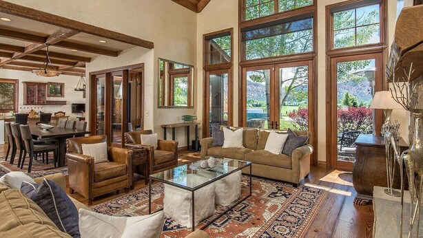 A spacious living room with a high ceiling, large windows, and a cozy seating area. - Luxury House in Gated Community (Carbondale)