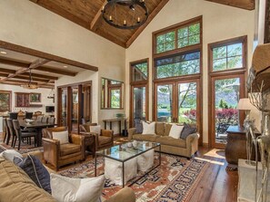 A spacious living room with a high ceiling, large windows, and a cozy seating area. - Luxury House in Gated Community (Carbondale)