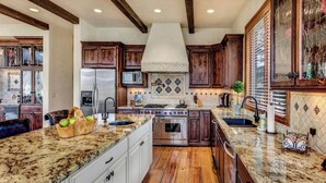 A spacious kitchen with granite countertops, wooden cabinets, and a central island. - Luxury House in Gated Community (Carbondale)