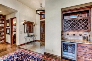 A spacious hallway with wooden flooring, a patterned rug, and a built-in bookshelf.