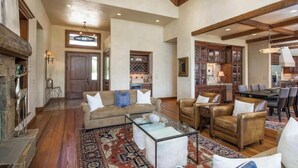 A spacious living area with a high ceiling, wooden beams, and a fireplace. There are multiple seating areas with sofas and a coffee table. - Luxury House in Gated Community (Carbondale)