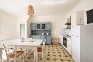 A kitchen with white cabinets, a dining table with chairs, and a patterned floor.