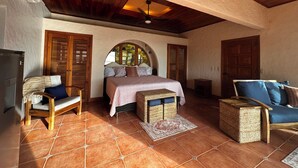 A spacious bedroom with a large bed, wooden furniture, and a tiled floor.