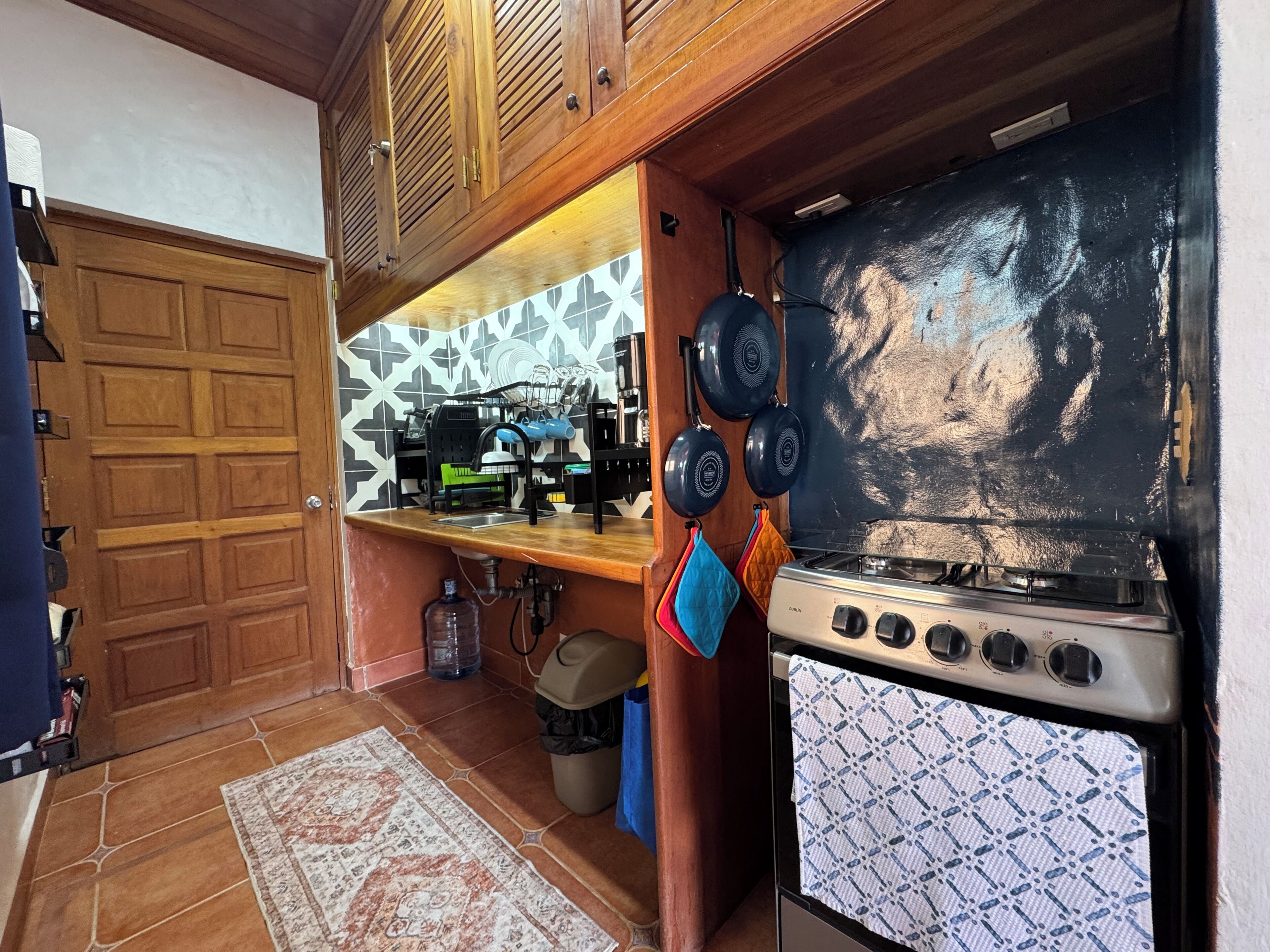 Una cocina con estufa, ollas colgantes y salpicadero de azulejos.