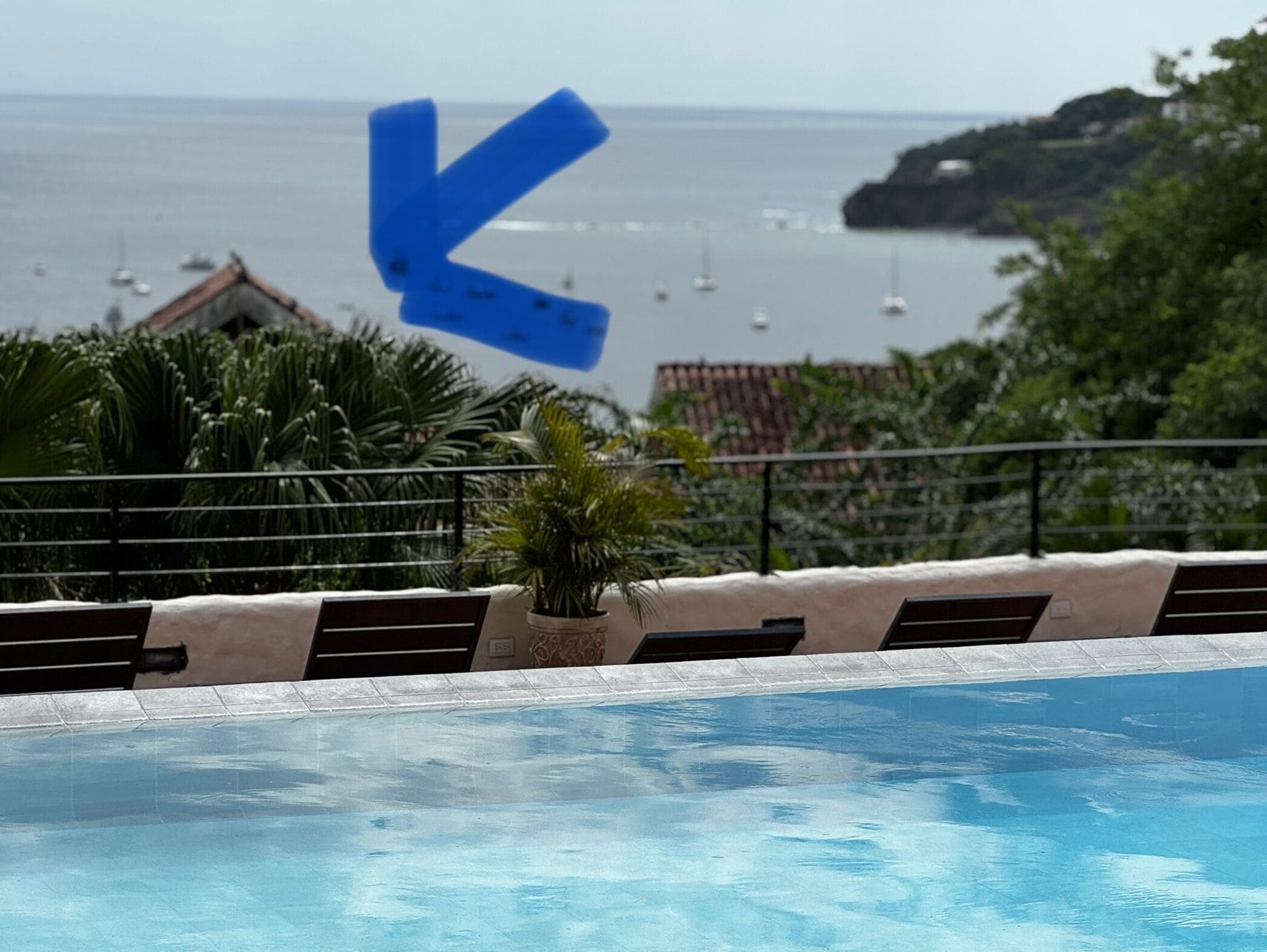 Zona de piscina con vista al mar y barcos.