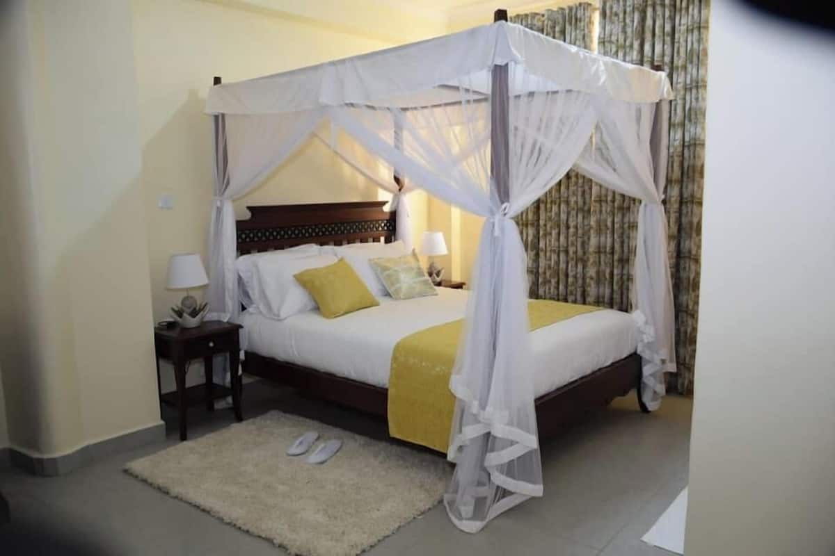 A four-poster bed with a canopy, a bedside table with a lamp, and a rug.