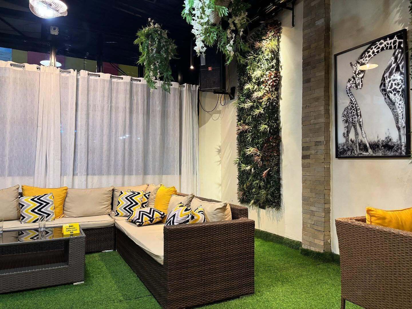A cozy seating area with a sofa and two chairs, a wall-mounted plant, and a giraffe-themed artwork.