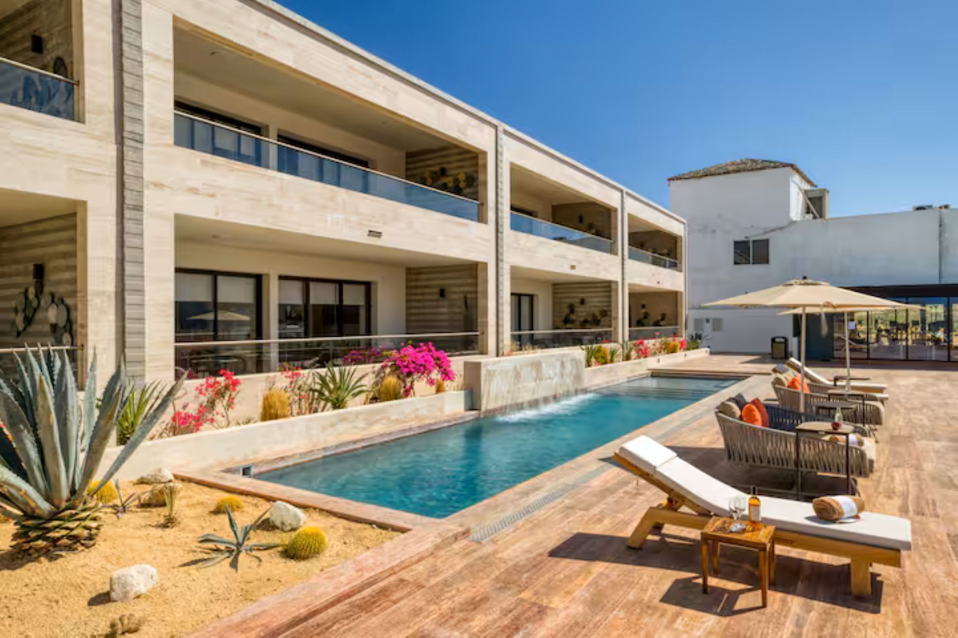 A modern hotel with a pool, outdoor seating, and a well-maintained garden.