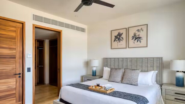 Ein Hotelzimmer mit Bett, Nachttischen, Deckenventilator und Bildern an der Wand.