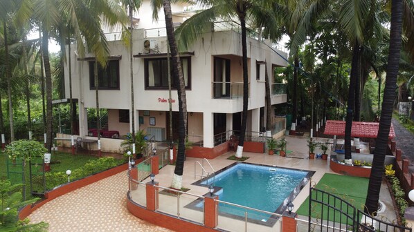 Ein Hotel mit Pool, Palmen und einer überdachten Sitzgelegenheit.