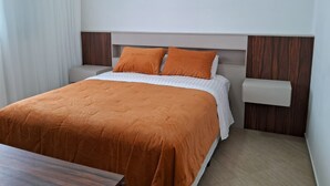 A hotel room with a bed, two bedside tables, and a wooden nightstand. - Apto Prédio Costa 1 c/ garagem no centro (São Roque)