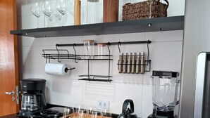 A modern kitchen with a wooden countertop, a coffee maker, a kettle, a blender, and a built-in oven. - Apto Prédio Costa 1 c/ garagem no centro (São Roque)