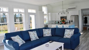 A modern kitchen with white cabinets, a central island, and a dining area. - Blue Horizon Cottage – Steps From Private Beach, Family-Friendly Coastal Retreat (Prince Edward Island)