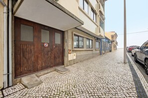 A cobblestone street with a wooden door, a mailbox, and a parked car.